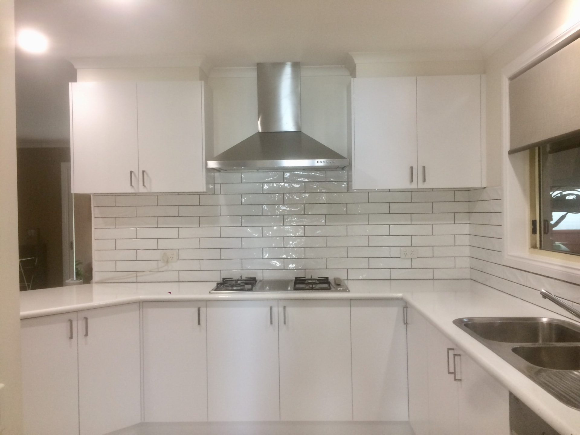 Resurfaced white kitchen with subway splashback and rangehood